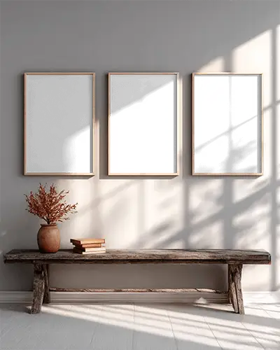 Three Vertical Canvas Mockups Hanging Above Wooden Bench With Vase And Books