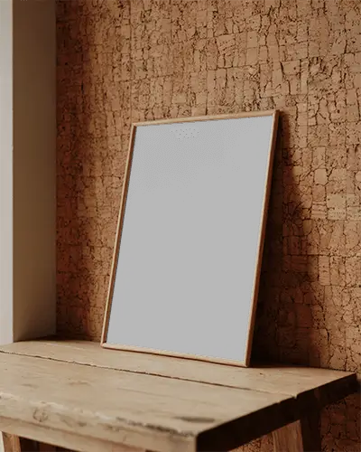 Rustic Wooden Table With Minimalist Framed Poster Mockup Leaning Against Textured Wall