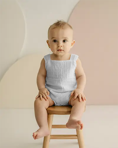Cute Baby Wearing Onesie Sitting On Wooden Chair Minimalist Background Studio Shot