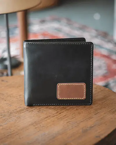 Cozy Indoor Wallet Mockup Black Leather Bifold Placed On Wooden Table With Colorful Rug Background Casual And Warm Setting 0107