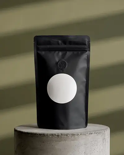 Front View Black Coffee Pouch Sticker Mockup On Concrete Pedestal With Round Label And Striped Background 0195