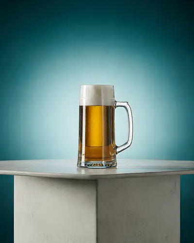 Classic Beer Mug Sticker Mockup On Glass With Foam Head And Light Gradient Background On Stone Platform 0203