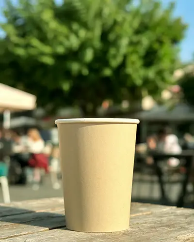 Outdoor Coffee Cup Sticker Mockup On Wooden Table In Blurred Cafe Setting With Natural Daylight 0235