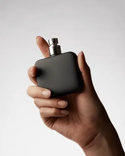 Hand Holding Perfume Bottle Sticker Mockup On Clean Gradient Background In Closeup Scene