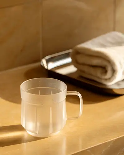 Realistic Clear Mug Sticker Mockup Placed On Marble Counter With Towel Tray Beside