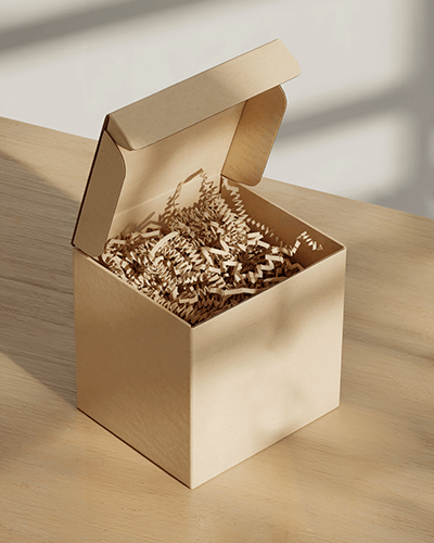Open Cardboard Box Sticker Mockup With Kraft Paper Fill And Natural Light Shadow