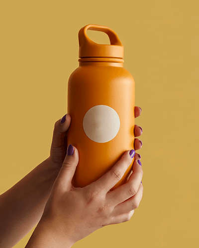Bright Orange Bottle Sticker Mockup In Hand With Round Label And Minimal Background For Branding 0274