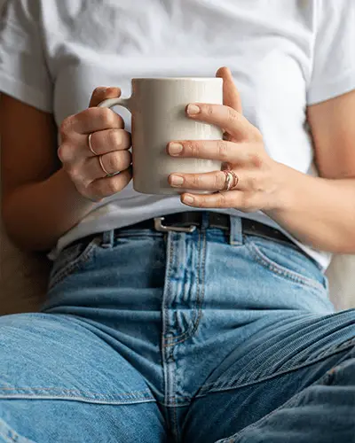 closeup-human-hands-grasping-coffee-cup-sticker-mockup-with-rings-on-fingers-stylish-casual-look