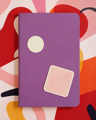 minimal-round-and-square-sticker-mockup-on-notebook-against-graphic-backdrop