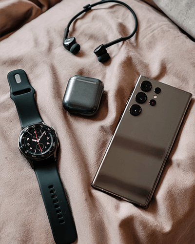 premium-smartwatch-with-analog-dial-smartphone-and-wireless-earbuds-on-soft-fabric-sticker-mockup