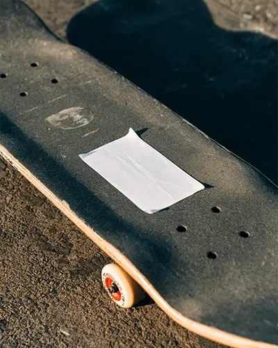 blank-rectangular-sticker-on-skateboard-deck-surface-outdoor-street-scene-mockup