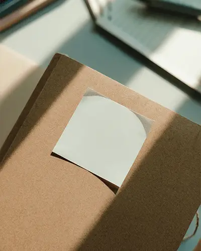 Minimalistic Sticky Note Mockup On Recycled Paper Covered Notebook With Natural Light
