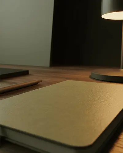textured-notebook-sticker-mockup-on-wooden-desk-with-pen-and-lamp-lighting