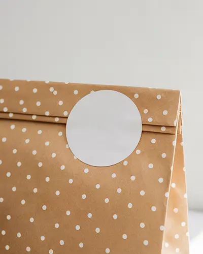 Round Blank Sticker Mockup On Polka Dot Paper Bag Ideal For Branding Labels And Packaging Designs