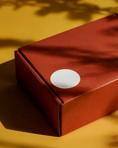 White Round Sticker Mockup On Craft Paper Box For Custom Label And Packaging Presentation
