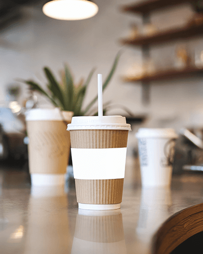 Coffee Shop Cup Sticker Mockup Close Up On Counter In Cozy Cafe Setting