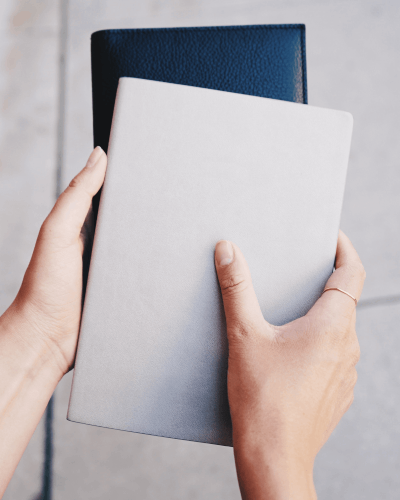 Hands Holding Gray Notebook Sticker Mockup Outdoors For Minimalistic And Modern Presentation