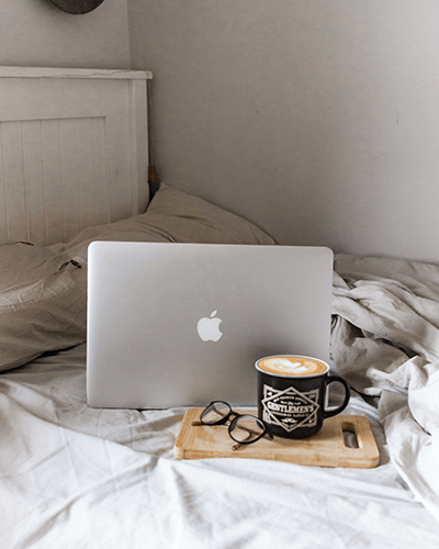 Cozy Bedroom Laptop Sticker Mockup With Coffee And Glasses On Wooden Board For Relaxed Home Office Vibe