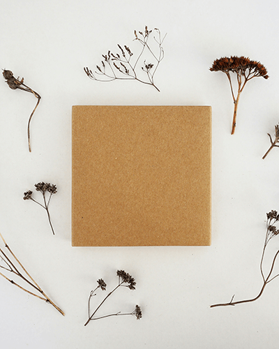 Kraft Box Sticker Mockup Surrounded By Dried Flowers On White Background For Organic And Rustic Look