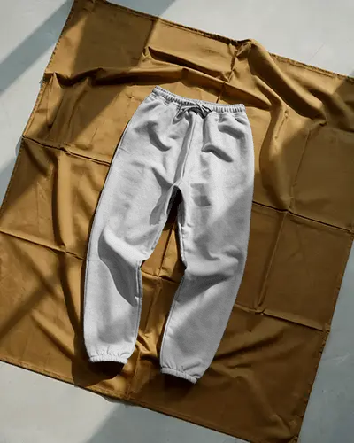 Sunlit Flatlay Sweatpants Mockup On Brown Fabric With Soft Shadows And Elevated Texture