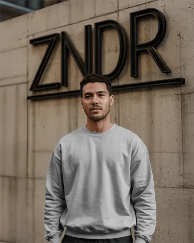 Urban Wall Sweatshirt Mockup Male Model Standing In Front Of Modern Building Signage Moody Lighting Minimalist Streetwear Vibe