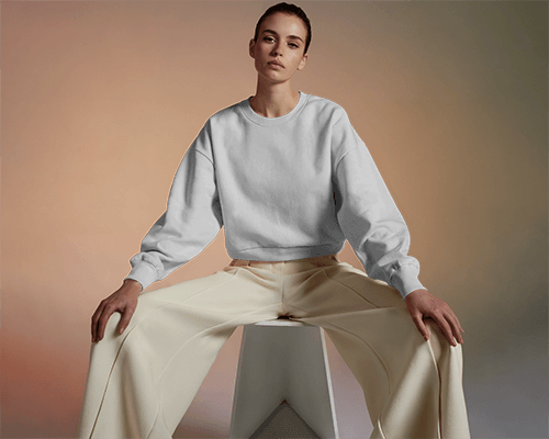 Neutral Tone Sweatshirt Mockup Female Model Sitting With Wide Pose On Minimalist Background