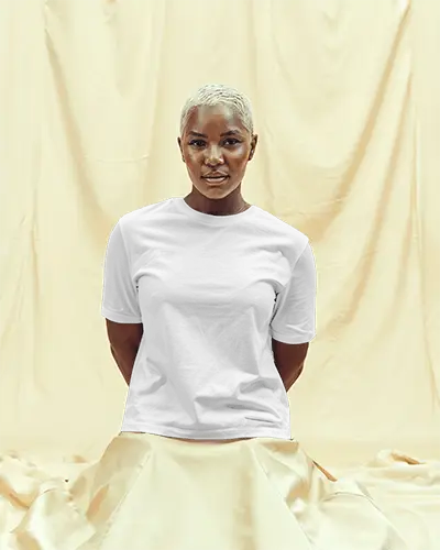 Artistic T Shirt Display Mockup Bold Model In White Tee Sitting In Soft Golden Drape Environment