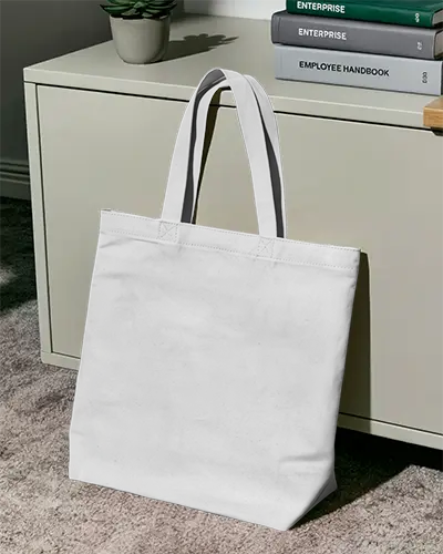 Clean Office Tote Bag Mockup White Canvas Bag Leaning On Drawer With Books And Sunlight Shadow 0288