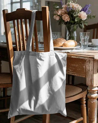 tote-bag-mockup-hanging-on-wooden-chair-in-cozy-dining-room-setting