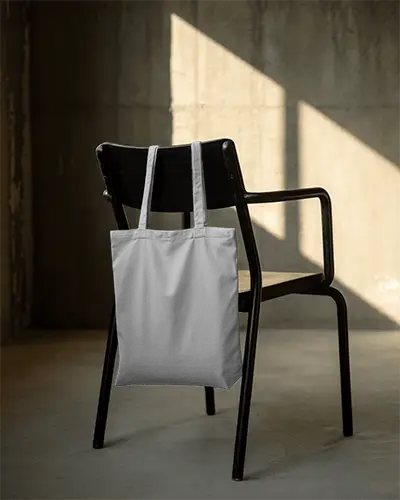 rustic-industrial-tote-bag-mockup-on-black-chair-sunlit-wall-background-urban-minimal-style