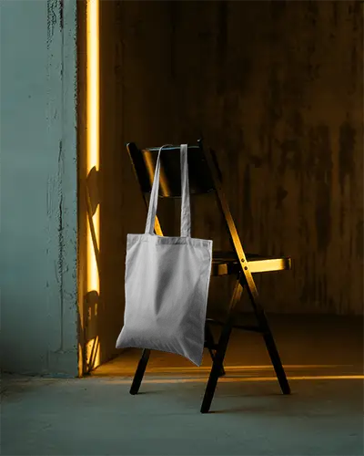 artistic-shadow-tote-bag-mockup-hanging-on-folding-chair-with-golden-light-modern-aesthetic