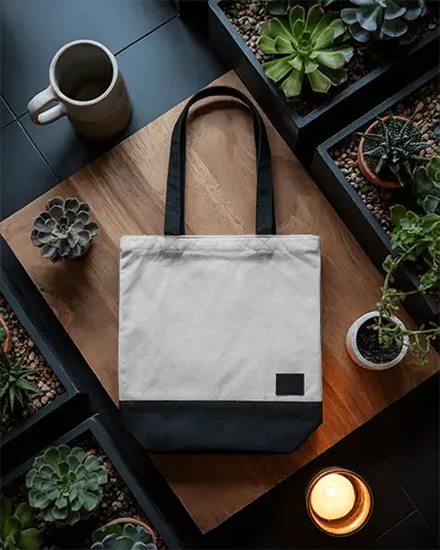 Top View Tote Bag Mockup On Wooden Table Surrounded By Plants Candle Cozy Natural Decor