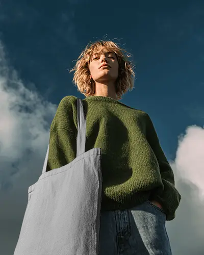 Low Angle Outdoor Totebag Mockup With Female Model Under Blue Sky And Natural Daylight