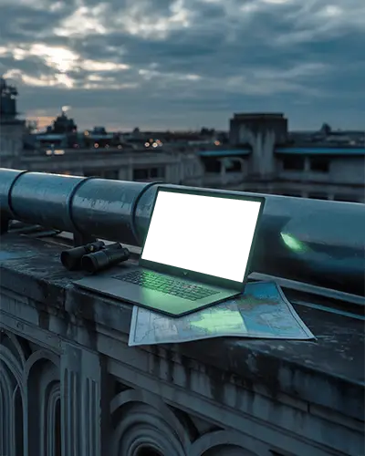 razer-laptop-mockup-on-urban-rooftop-with-binoculars-and-map-under-dramatic-sky