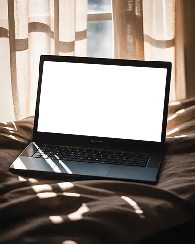 razer-laptop-mockup-on-bed-with-soft-sunlight-streaming-through-curtains-cozy-scene