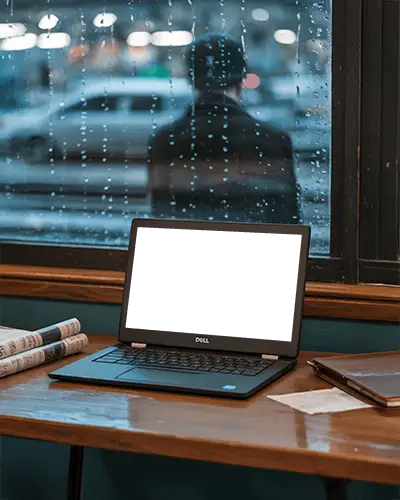Dell Laptop Mockup On Wooden Desk By Window With Raindrops And Blurred Figure Outside