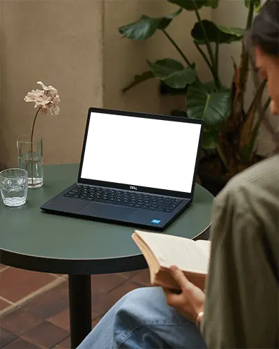 Dell Laptop Mockup On Green Table In Cozy Outdoor Space With Person Reading And Minimal Decor
