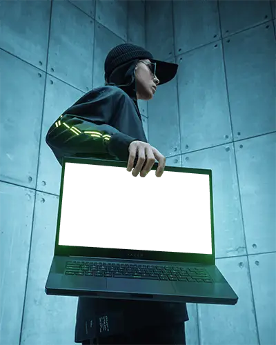 Razer Gaming Laptop Mockup Held By Person In Cyberpunk Outfit Against Industrial Grey Wall Backdrop
