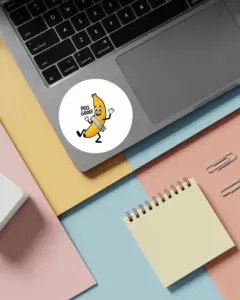 blank circle sticker mockup on modern laptop with office supplies on colorful background